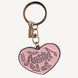 A pink heart-shaped metal keychain charm with 'Austin' and local landmarks engraved, attached to a gold-tone split ring and clasp, on a light gray background.