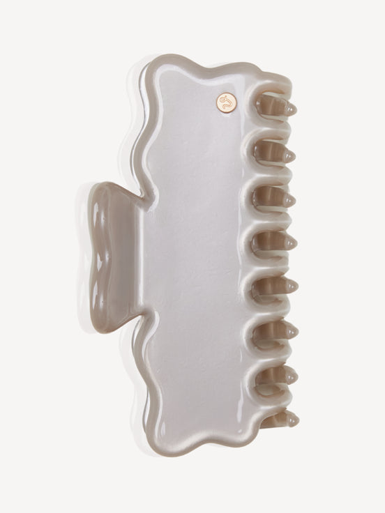 A glossy, wavy cellulose acetate hair claw clip in a light silver color, shown from a top-down view on a clean white background.