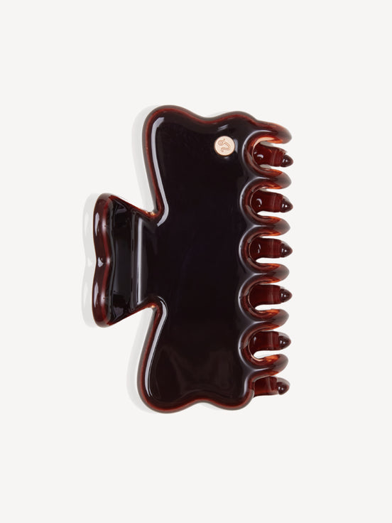 A glossy brown cellulose acetate hair claw clip, shown from a top-down view on a light gray background.